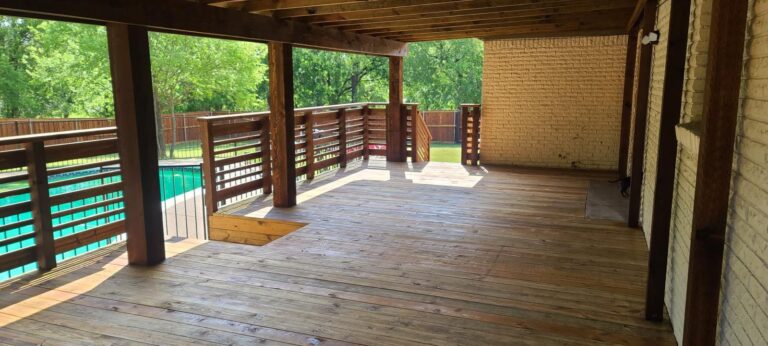 Covered deck with horizontal cable railing overlooking a backyard pool in the DFW area