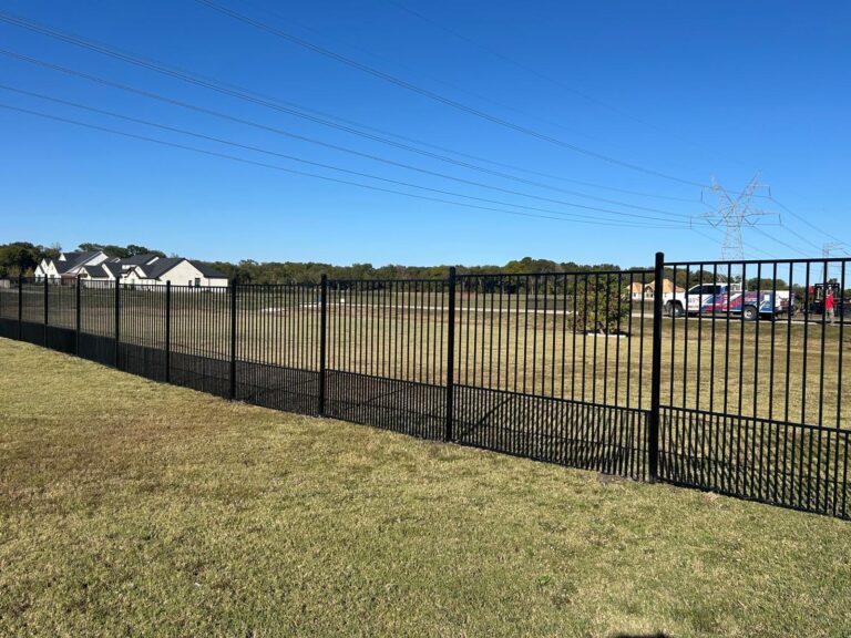 Black aluminum commercial fence running the length of a property boundary in DFW