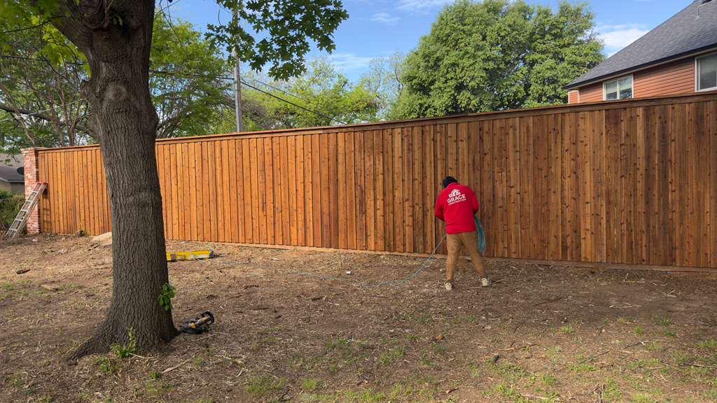 Grace Construction crew staining a newly installed cedar board-on-board fence