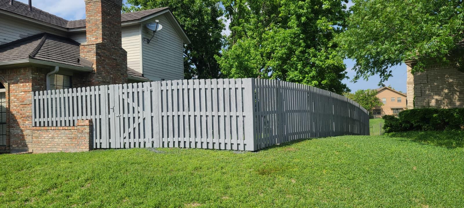 Gray painted wood picket fence and matching gate at a corner yard